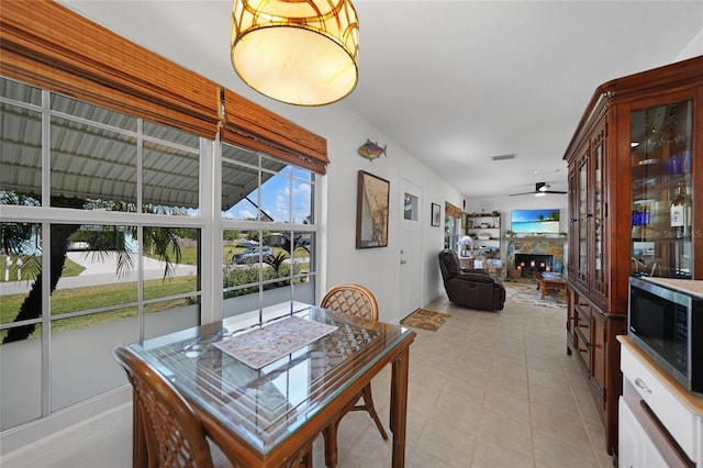 dining room featuring a stone fireplace and ceiling fan