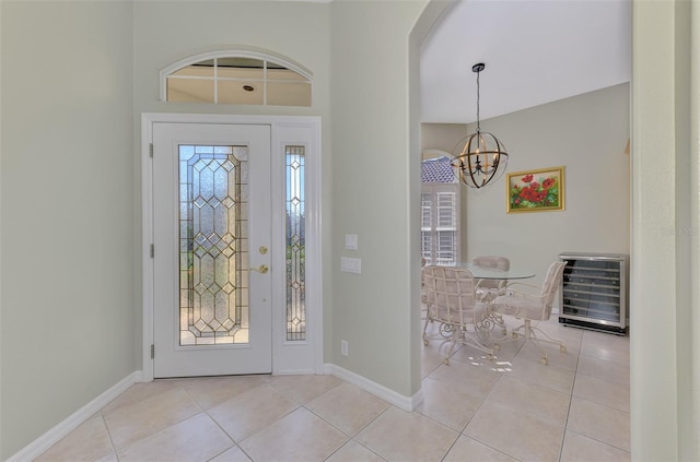 foyer with an inviting chandelier, a wealth of natural light, and light tile patterned floors