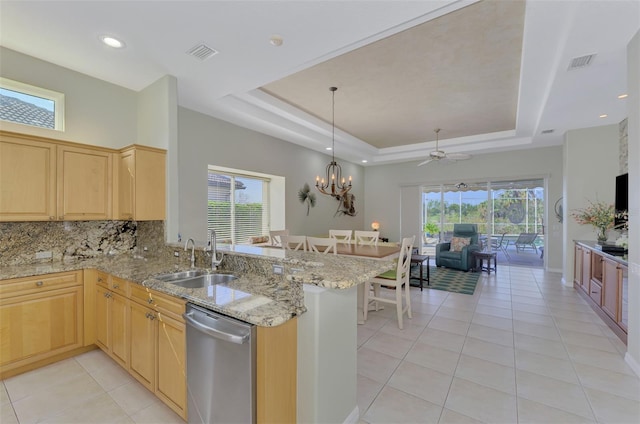 kitchen featuring a raised ceiling, dishwasher, and kitchen peninsula