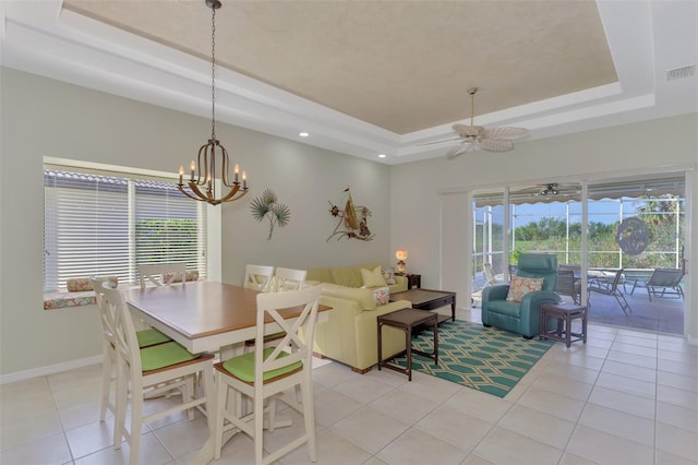 tiled dining room with a tray ceiling and ceiling fan with notable chandelier