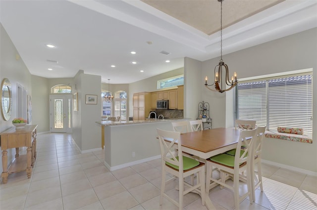 dining area featuring an inviting chandelier, a tray ceiling, and light tile patterned flooring