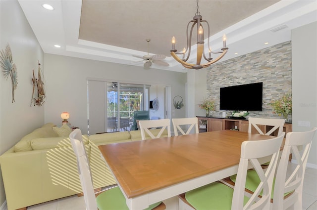 tiled dining space with a raised ceiling and ceiling fan with notable chandelier