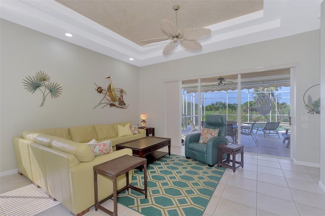 living room with light tile patterned floors, a tray ceiling, and ceiling fan