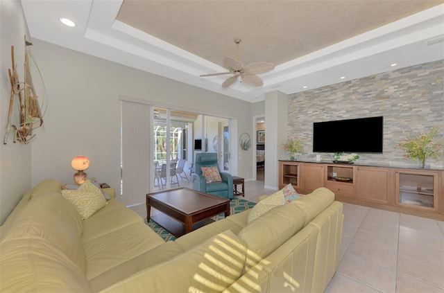 living room featuring light tile patterned floors, a raised ceiling, and ceiling fan