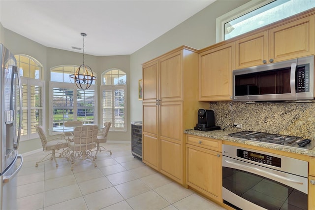 kitchen featuring appliances with stainless steel finishes, light brown cabinets, backsplash, and decorative light fixtures