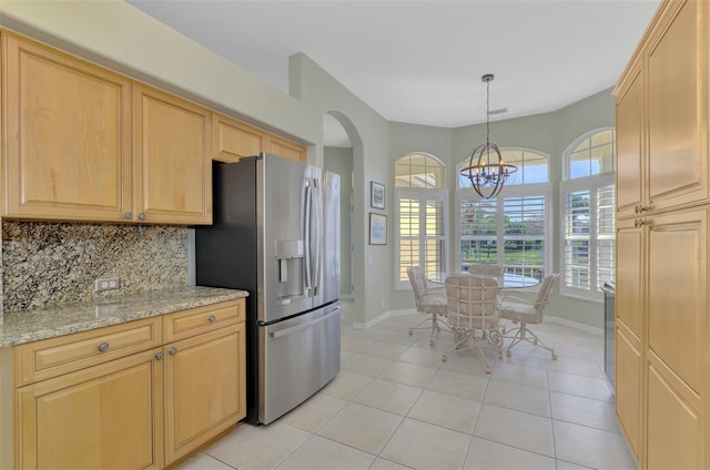 kitchen with pendant lighting, light brown cabinetry, tasteful backsplash, light stone counters, and stainless steel refrigerator with ice dispenser