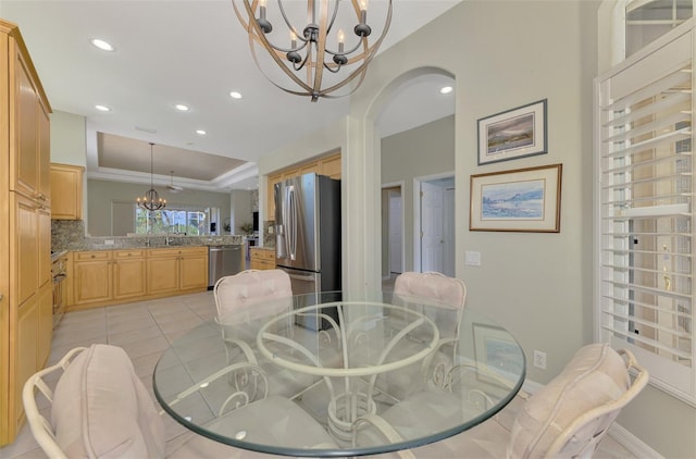 dining room with an inviting chandelier, a raised ceiling, and light tile patterned floors