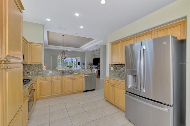 kitchen with appliances with stainless steel finishes, a tray ceiling, light stone countertops, and light brown cabinetry