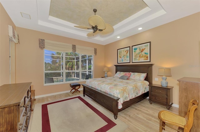 bedroom featuring a raised ceiling, ceiling fan, and light hardwood / wood-style floors