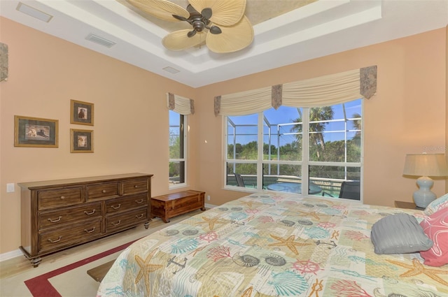 bedroom with access to outside, a raised ceiling, and ceiling fan