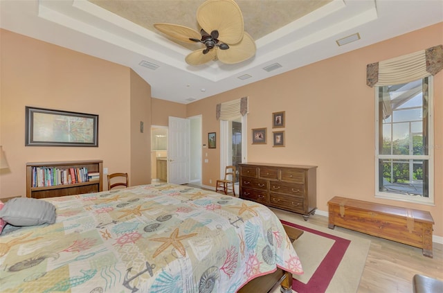 bedroom featuring a tray ceiling, light hardwood / wood-style floors, and ceiling fan