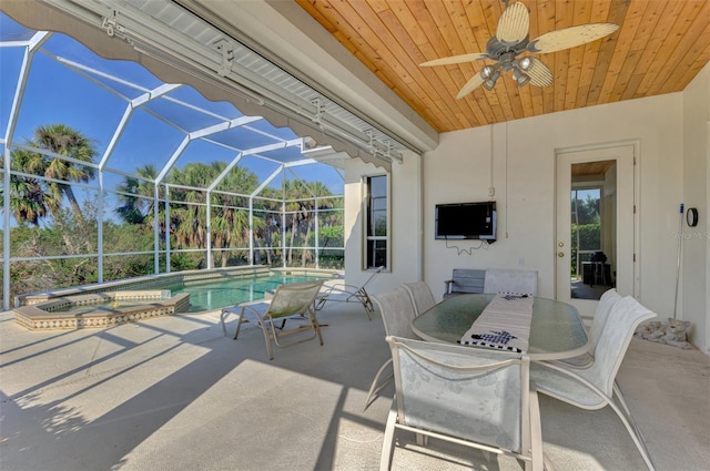 view of patio / terrace featuring a swimming pool with hot tub and glass enclosure