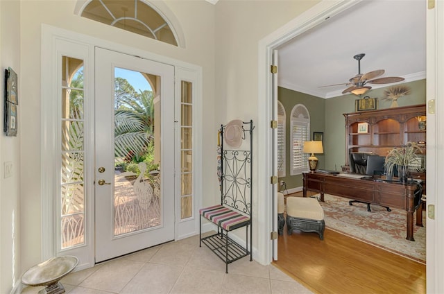 entryway with light tile patterned floors, ornamental molding, and ceiling fan