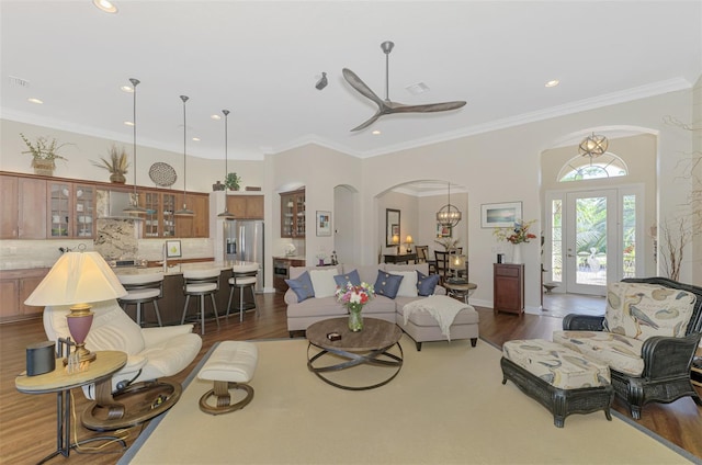 living room with dark hardwood / wood-style flooring, crown molding, and ceiling fan with notable chandelier