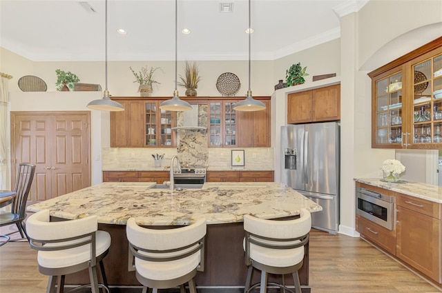 kitchen featuring stainless steel appliances, a center island with sink, sink, and pendant lighting