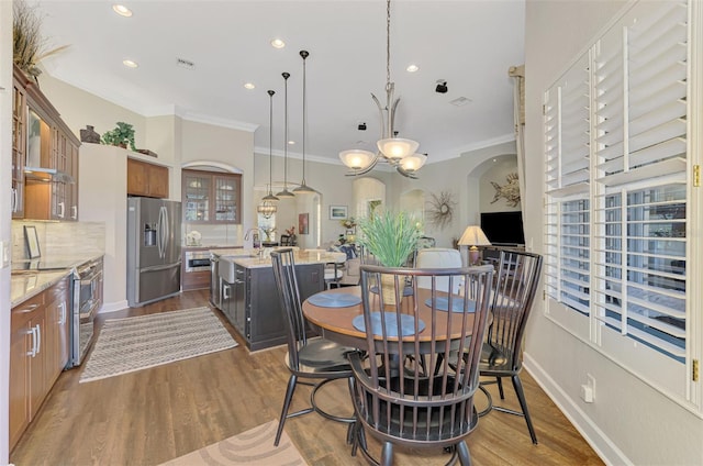 dining area with ornamental molding, dark hardwood / wood-style floors, and sink