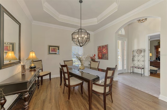 dining space featuring a raised ceiling, hardwood / wood-style floors, and a notable chandelier