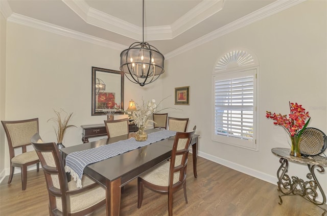 dining room with a raised ceiling, ornamental molding, hardwood / wood-style floors, and a chandelier