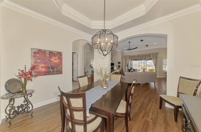 dining room with crown molding, wood-type flooring, and a raised ceiling