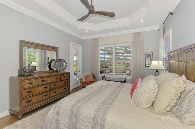 bedroom with hardwood / wood-style floors, a raised ceiling, access to outside, and crown molding