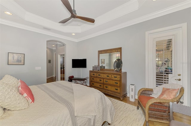 bedroom featuring crown molding, hardwood / wood-style floors, a tray ceiling, and ceiling fan