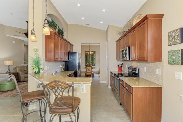 kitchen with a kitchen breakfast bar, stainless steel appliances, light tile patterned flooring, vaulted ceiling, and kitchen peninsula