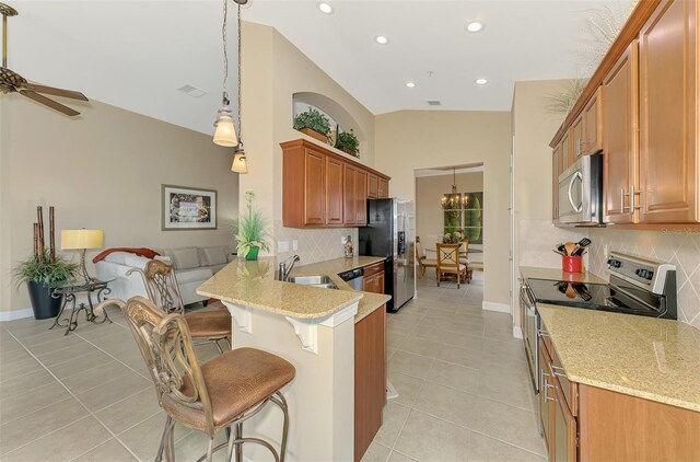 kitchen featuring a breakfast bar, sink, light tile patterned floors, kitchen peninsula, and stainless steel appliances