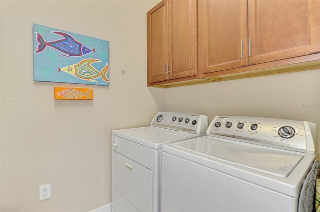 clothes washing area featuring cabinets and washing machine and dryer