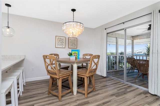 dining space featuring wood-type flooring and ceiling fan with notable chandelier