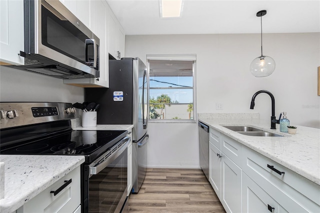 kitchen featuring sink, white cabinetry, light stone counters, pendant lighting, and stainless steel appliances