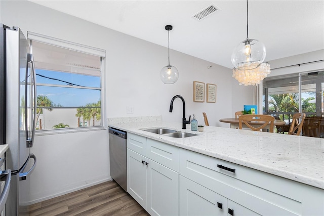 kitchen with stainless steel appliances, white cabinetry, hanging light fixtures, and sink