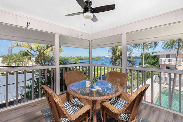 sunroom featuring a water view and ceiling fan