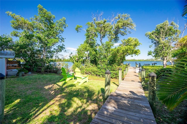 view of dock featuring a lawn and a water view