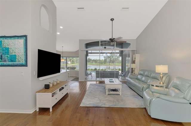 living room with light hardwood / wood-style flooring, high vaulted ceiling, and ceiling fan