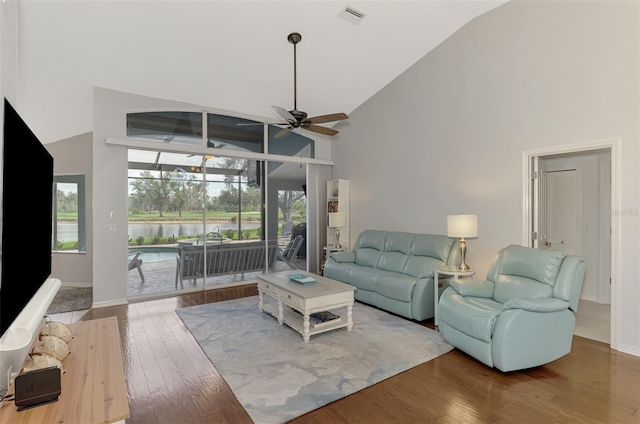 living room with hardwood / wood-style flooring, high vaulted ceiling, ceiling fan, and a water view