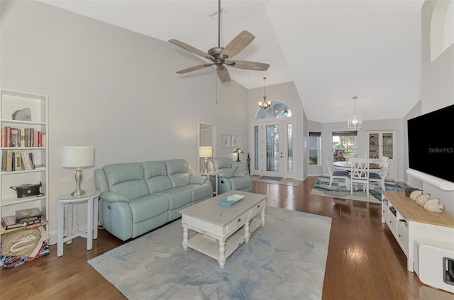 living room with dark hardwood / wood-style floors, ceiling fan with notable chandelier, high vaulted ceiling, and french doors