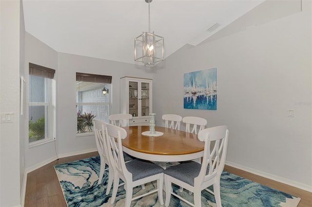 dining space with an inviting chandelier, hardwood / wood-style flooring, and vaulted ceiling