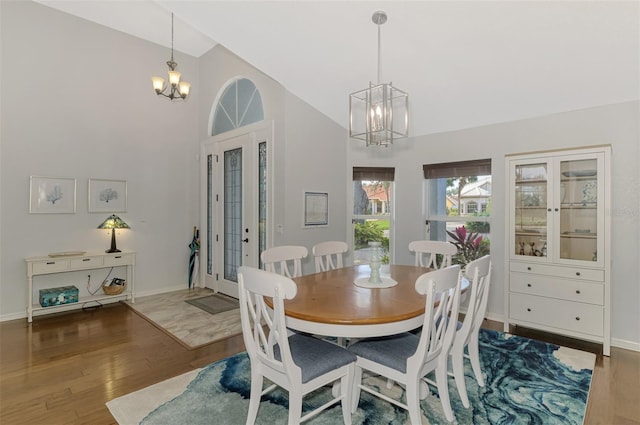 dining space with dark wood-type flooring, a chandelier, vaulted ceiling, and french doors