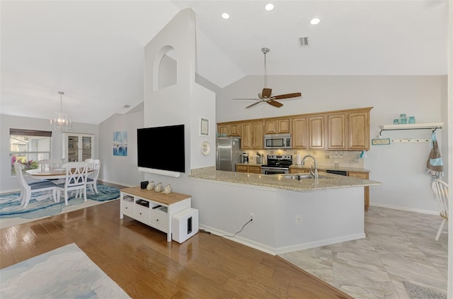 kitchen with sink, decorative light fixtures, appliances with stainless steel finishes, light stone countertops, and decorative backsplash