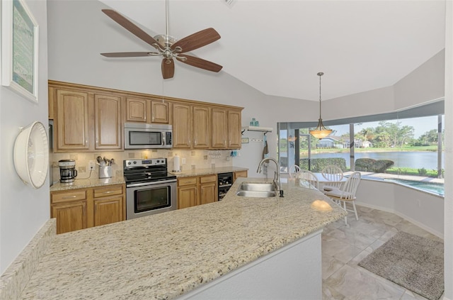 kitchen with lofted ceiling, sink, appliances with stainless steel finishes, a water view, and beverage cooler