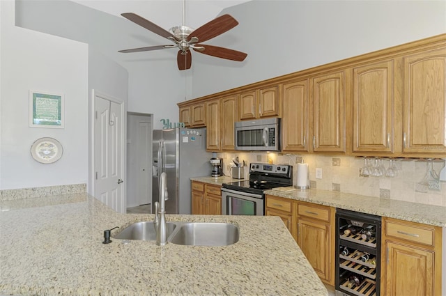 kitchen with sink, appliances with stainless steel finishes, light stone countertops, decorative backsplash, and beverage cooler