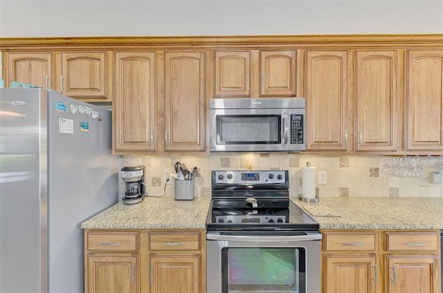 kitchen featuring light stone counters, backsplash, and stainless steel appliances