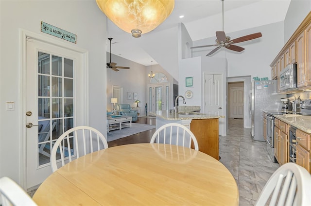 dining room featuring ceiling fan, sink, and high vaulted ceiling