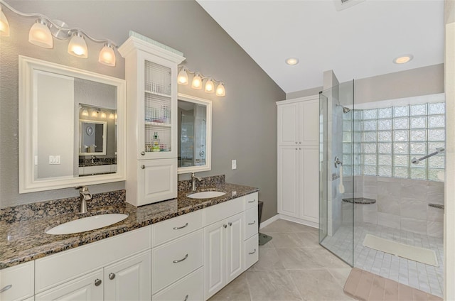 bathroom with tiled shower, vanity, vaulted ceiling, and tile patterned floors