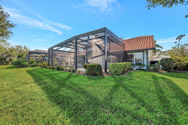 rear view of house featuring glass enclosure and a lawn