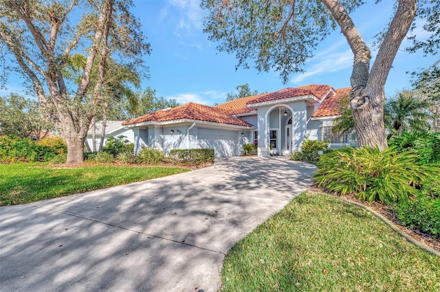 mediterranean / spanish home featuring a garage and a front lawn