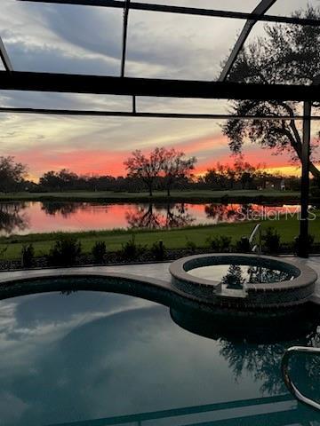 pool at dusk with a water view and glass enclosure