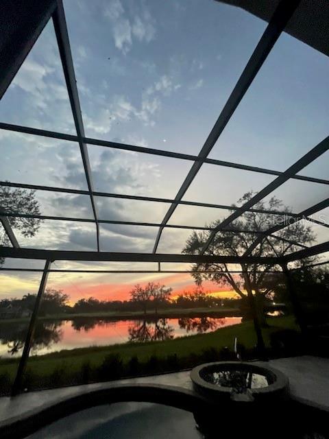 pool at dusk with a water view, an outdoor fire pit, and a lanai