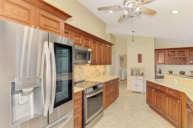 kitchen with brown cabinetry, decorative backsplash, lofted ceiling, stainless steel appliances, and light countertops