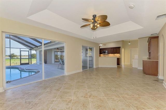 interior space featuring a raised ceiling, ceiling fan, and light tile patterned flooring